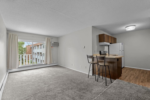 kitchen with under cabinet range hood, baseboard heating, a breakfast bar, and a wall mounted air conditioner