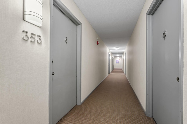 corridor with a textured ceiling and carpet floors