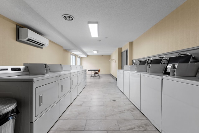 common laundry area featuring a textured ceiling, separate washer and dryer, and a wall mounted AC