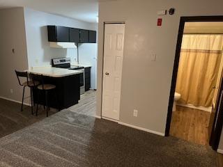 kitchen with stainless steel electric stove, a peninsula, a breakfast bar, and baseboards