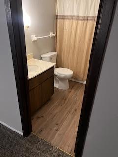 full bath with a shower with shower curtain, toilet, wood finished floors, and vanity