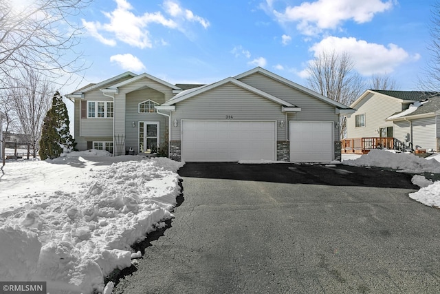 tri-level home featuring a garage and aphalt driveway