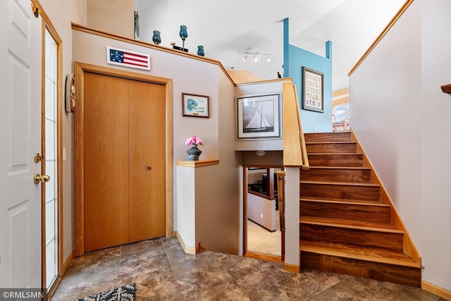 interior space featuring track lighting, stairs, and vaulted ceiling