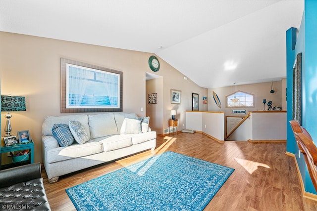 living area featuring baseboards, wood finished floors, and vaulted ceiling