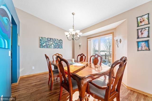 dining area with a notable chandelier, baseboards, light wood-style floors, and vaulted ceiling