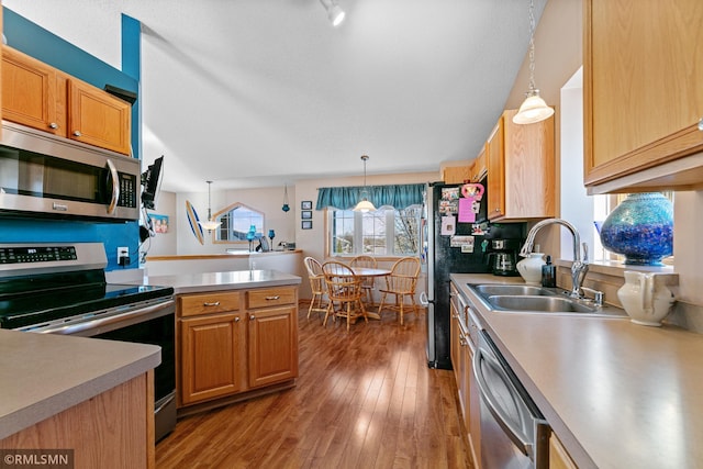 kitchen with a sink, light wood finished floors, appliances with stainless steel finishes, and light countertops