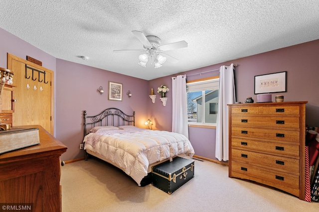 bedroom featuring a textured ceiling, a ceiling fan, and light carpet