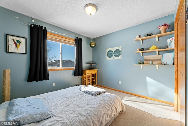 bedroom featuring carpet flooring, a textured ceiling, and baseboards