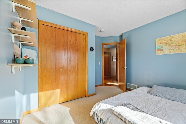 carpeted bedroom with a closet, baseboards, a textured ceiling, and visible vents