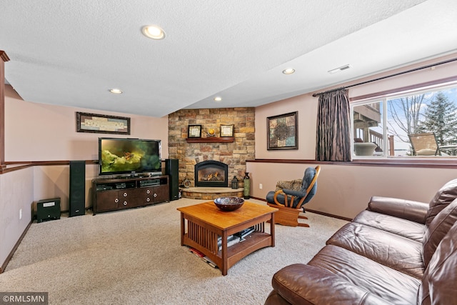 living room with visible vents, a textured ceiling, a stone fireplace, and carpet