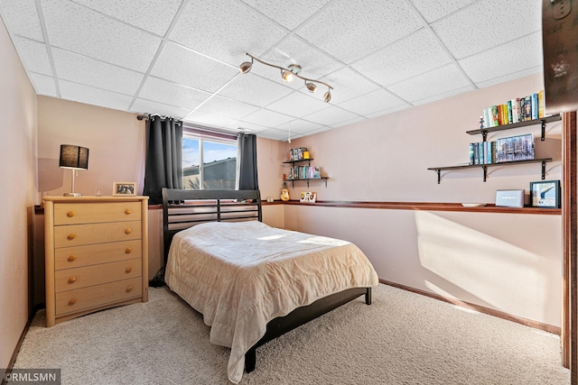 bedroom with light carpet, a drop ceiling, and baseboards