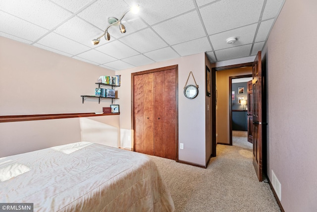 carpeted bedroom featuring a drop ceiling, baseboards, a closet, and visible vents