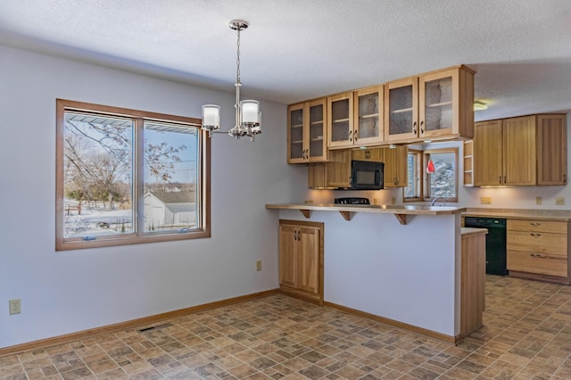 kitchen featuring baseboards, light countertops, a kitchen breakfast bar, a peninsula, and black appliances