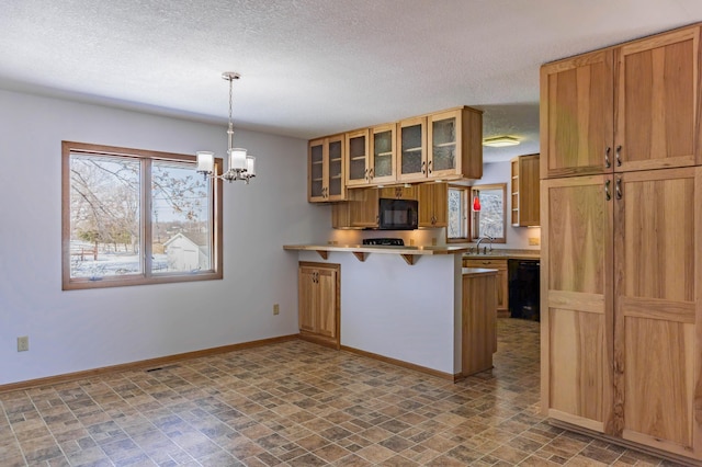 kitchen featuring baseboards, a peninsula, black appliances, glass insert cabinets, and a kitchen breakfast bar