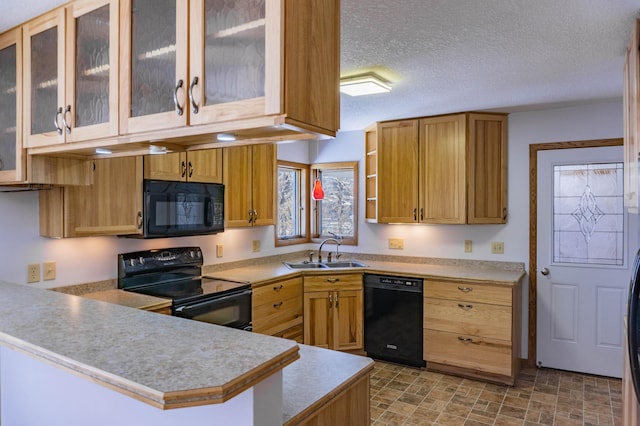 kitchen featuring black appliances, a sink, a textured ceiling, a peninsula, and light countertops