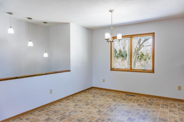 spare room with a notable chandelier, visible vents, a textured ceiling, and baseboards