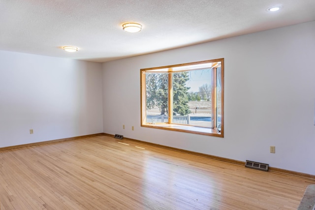 spare room with visible vents, light wood-style flooring, and baseboards