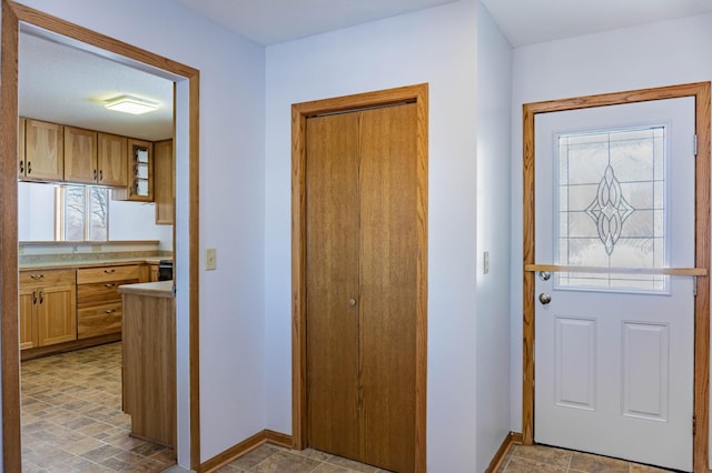 doorway to outside with stone finish floor and baseboards