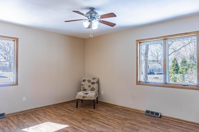 unfurnished room featuring visible vents, baseboards, wood finished floors, and a ceiling fan