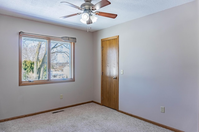 spare room with baseboards, light carpet, a textured ceiling, and ceiling fan