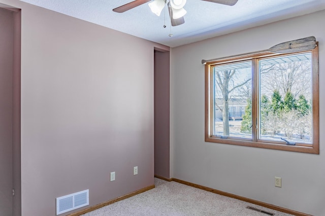 carpeted empty room with visible vents, ceiling fan, a textured ceiling, and baseboards