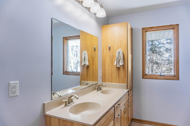 bathroom featuring double vanity, baseboards, and a sink