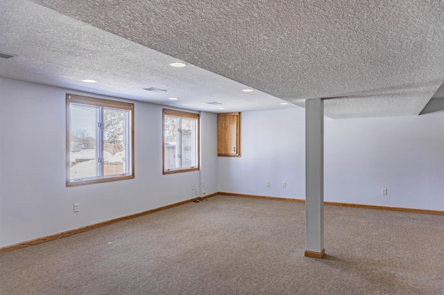 basement with visible vents, baseboards, light colored carpet, and a textured ceiling