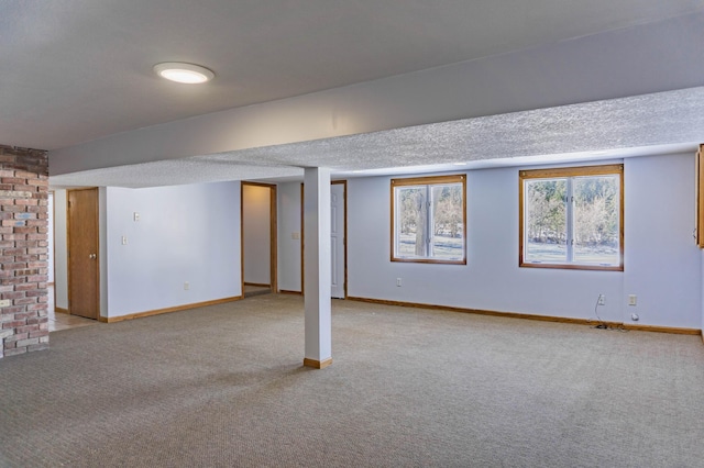 below grade area featuring baseboards, light colored carpet, and a textured ceiling