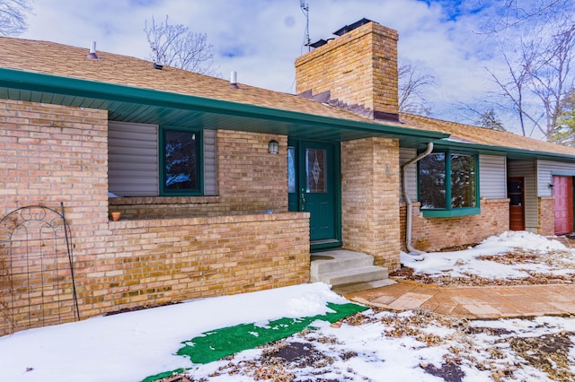 exterior space featuring brick siding, a chimney, and a shingled roof