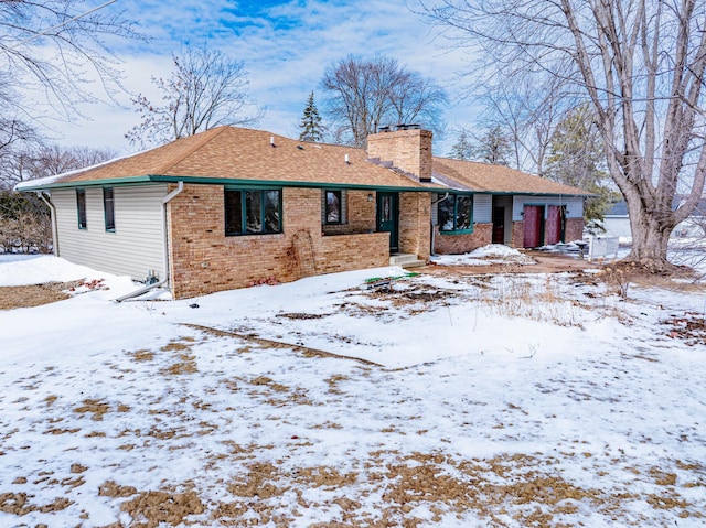 view of front of property featuring a garage, brick siding, roof with shingles, and a chimney