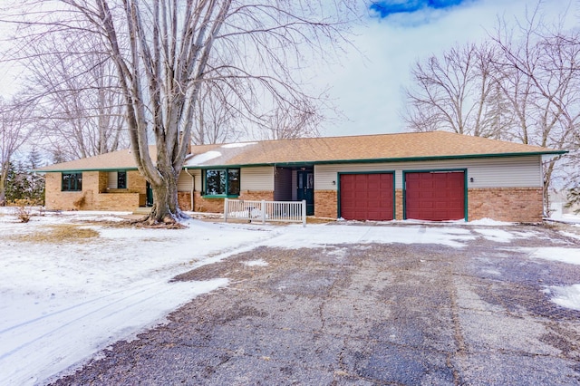 single story home featuring driveway, brick siding, a porch, and an attached garage