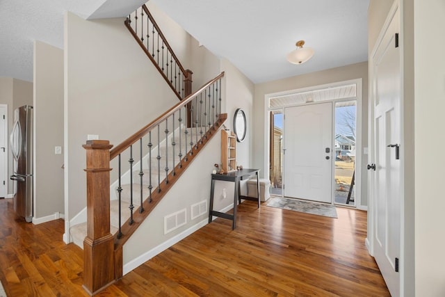 foyer entrance with stairway, wood finished floors, visible vents, and baseboards