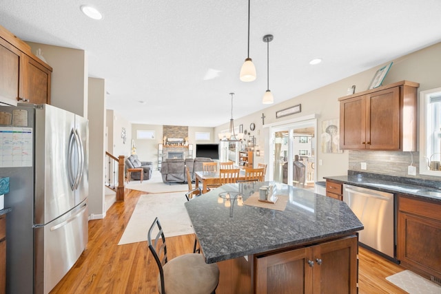 kitchen featuring pendant lighting, a kitchen bar, decorative backsplash, appliances with stainless steel finishes, and light wood-style floors