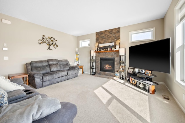 living area featuring visible vents, baseboards, carpet, and a stone fireplace