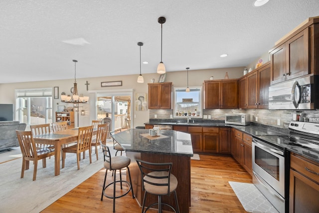 kitchen featuring light wood-type flooring, a kitchen breakfast bar, a center island, stainless steel appliances, and decorative backsplash