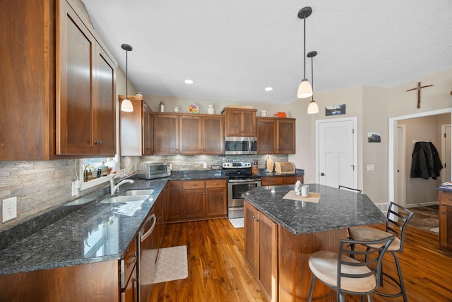 kitchen with dark wood finished floors, a kitchen breakfast bar, stainless steel appliances, and a sink