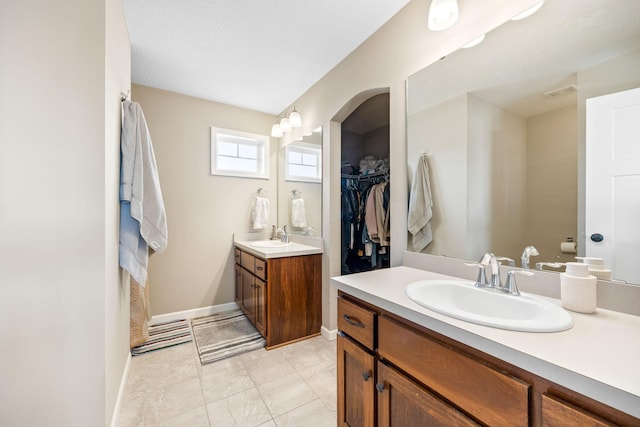 full bathroom with two vanities, visible vents, baseboards, and a sink