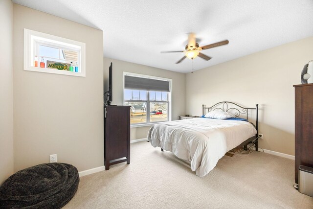 carpeted bedroom featuring baseboards, a textured ceiling, and a ceiling fan