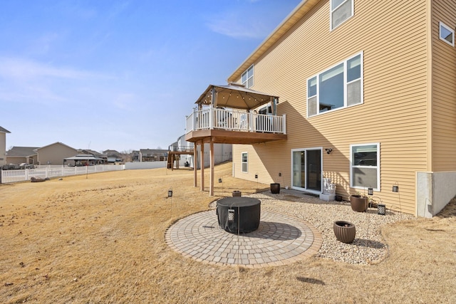 back of property with a deck, fence, and an outdoor fire pit