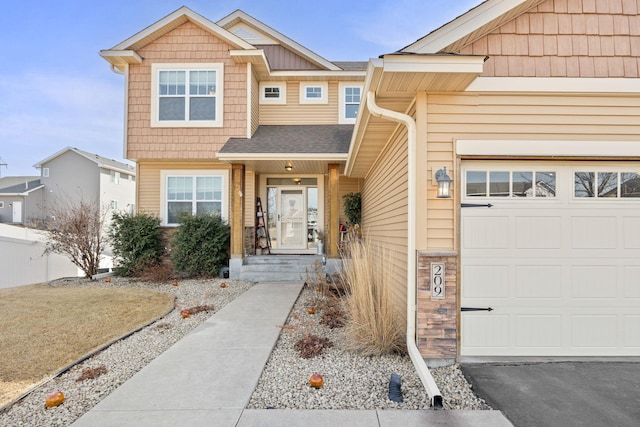 view of front of home featuring driveway, stone siding, fence, roof with shingles, and an attached garage