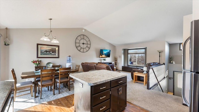 kitchen with open floor plan, light countertops, vaulted ceiling, light wood-style flooring, and freestanding refrigerator