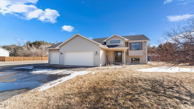 view of front of property featuring an attached garage, fence, and driveway