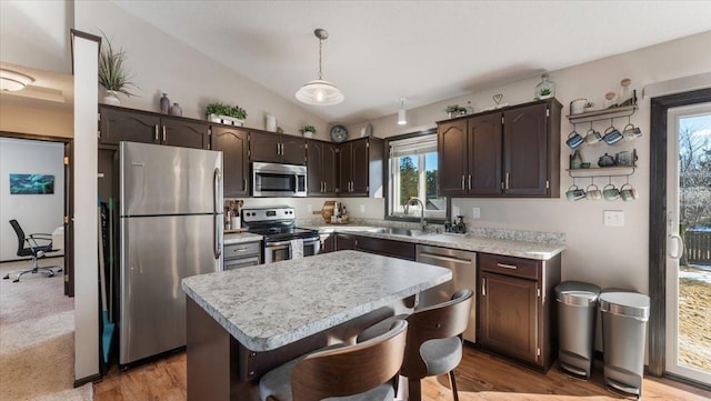 kitchen with dark brown cabinetry, light countertops, lofted ceiling, stainless steel appliances, and a sink