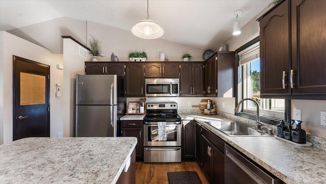 kitchen featuring dark brown cabinetry, light countertops, lofted ceiling, stainless steel appliances, and a sink