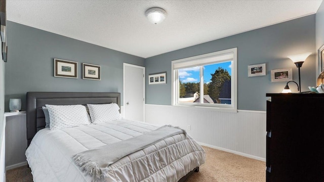 carpeted bedroom with wainscoting and a textured ceiling