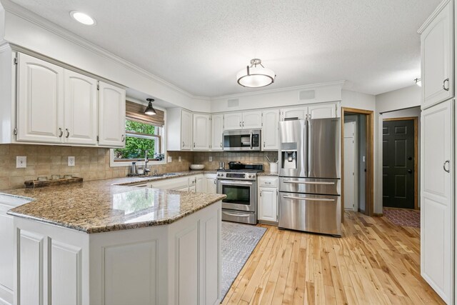 2415 Field Ct, Saint Cloud, MN 56301 - kitchen featuring appliances with stainless steel finishes, a peninsula, a sink, light wood-style flooring, and white cabinets