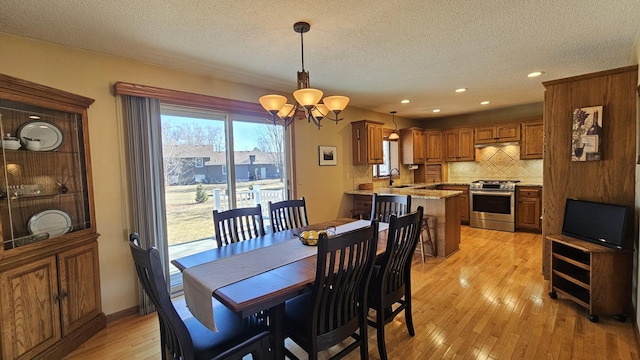 dining area featuring a chandelier, recessed lighting, a textured ceiling, and light wood-type flooring