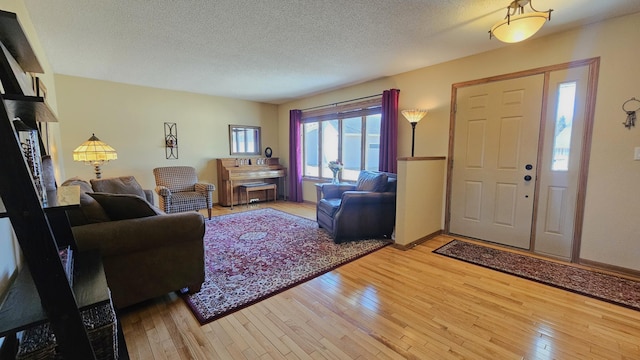 living area with light wood-style floors, baseboards, and a textured ceiling