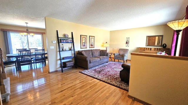 living area featuring a textured ceiling, an inviting chandelier, and light wood-style flooring