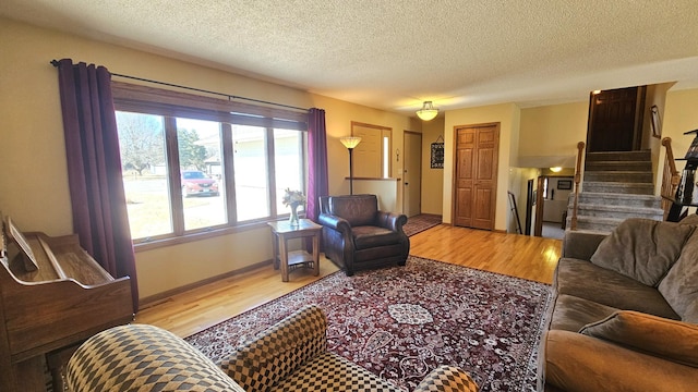 living area with stairway, a textured ceiling, and wood finished floors